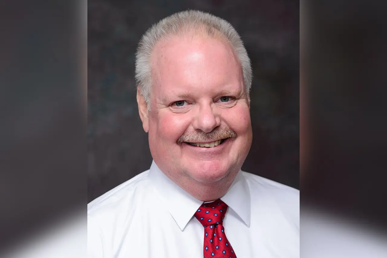 Here's an alt tag for the image: Smiling man in white shirt and red tie.