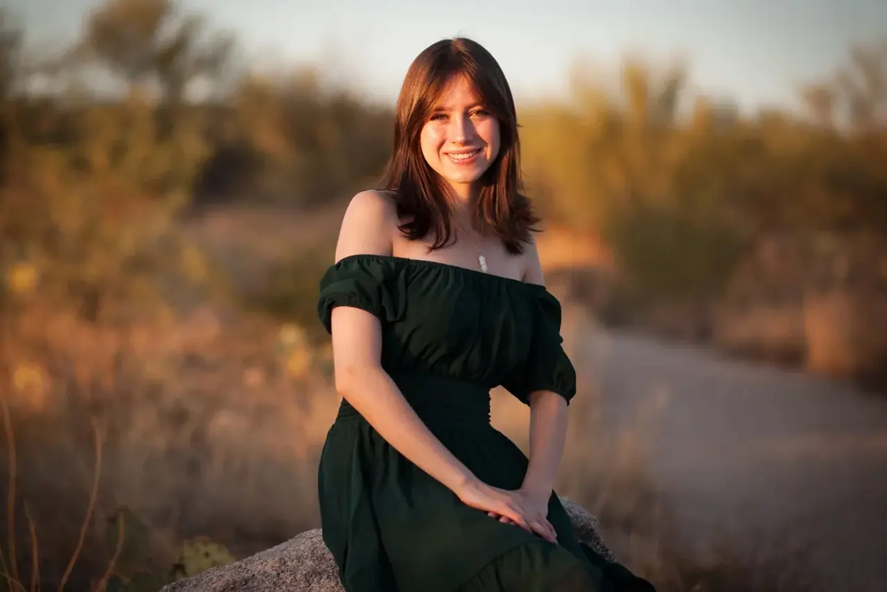 Smiling woman in green off-shoulder dress.