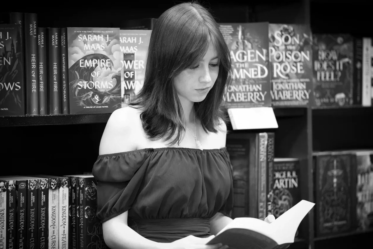 Woman reading book in bookstore.