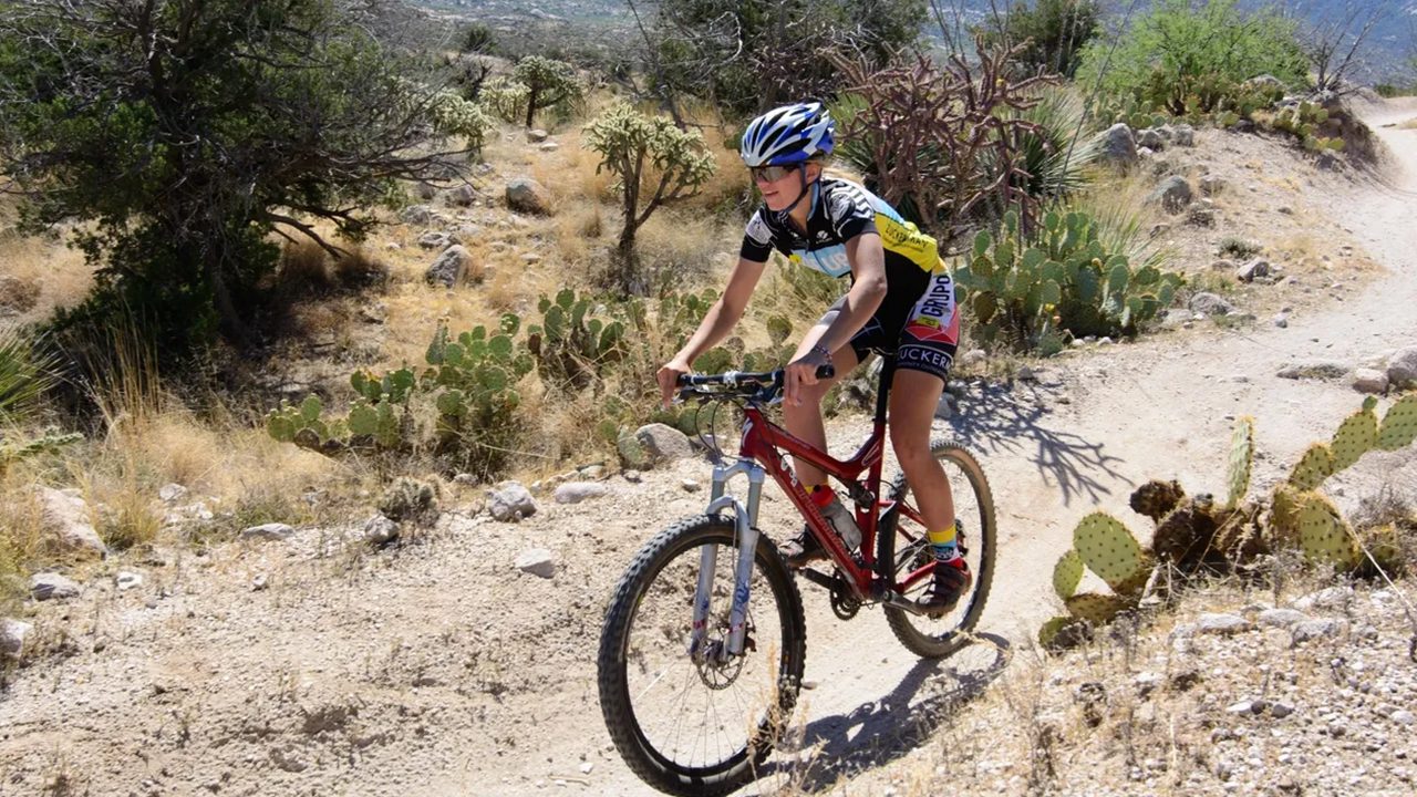 Woman mountain biking on desert trail.