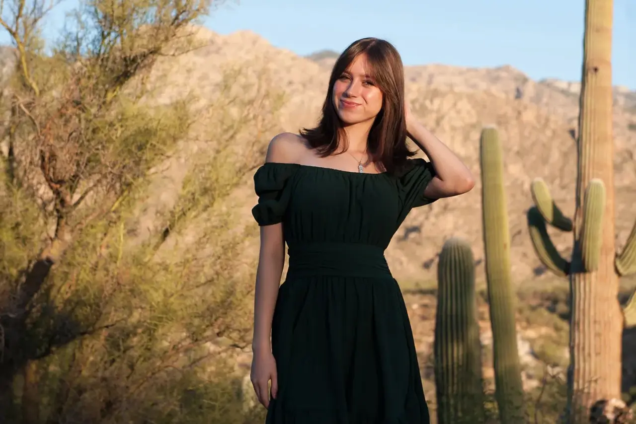 Woman in green dress in desert landscape.