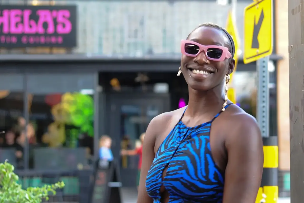 Smiling woman in pink sunglasses and blue dress.