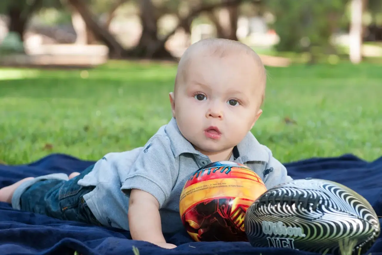 Baby boy playing with footballs outdoors.